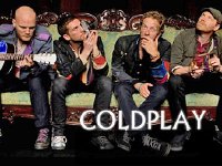 Coldplay  Coldplay band member seated on a couch. Guy Berryman and William Champion are wearing worn black and white Chuck Taylors.